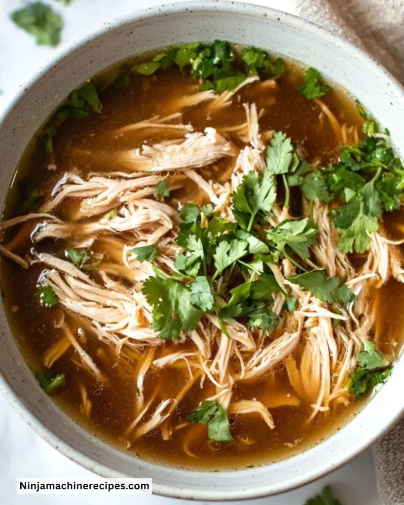 Bowl of steaming Crockpot Chicken Pho garnished with herbs and lime