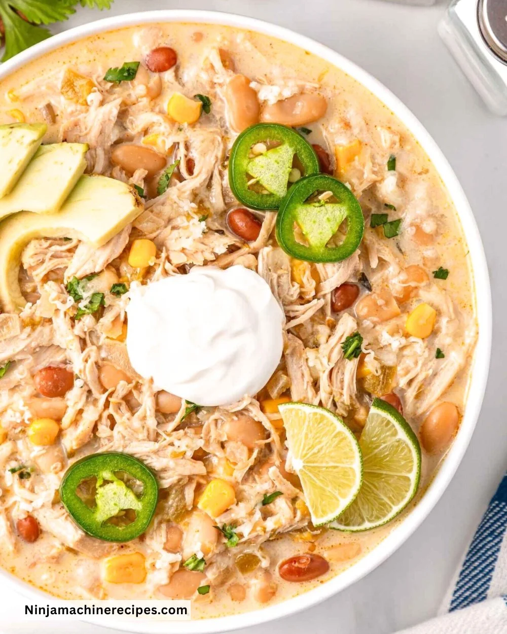 Bowl of creamy Crockpot white chicken chili topped with cilantro and avocado