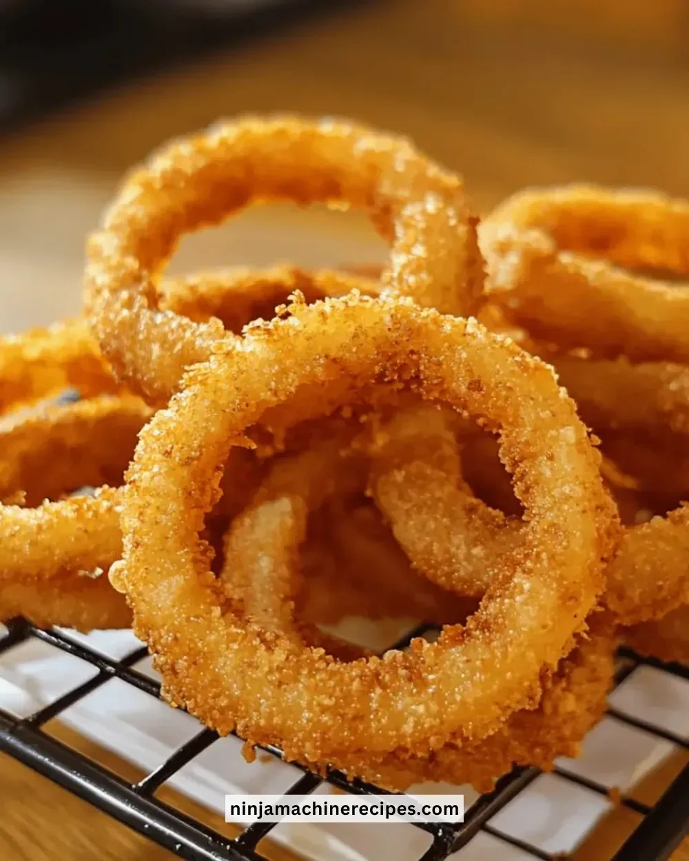 Golden crispy onion rings served with dipping sauce on a plate.