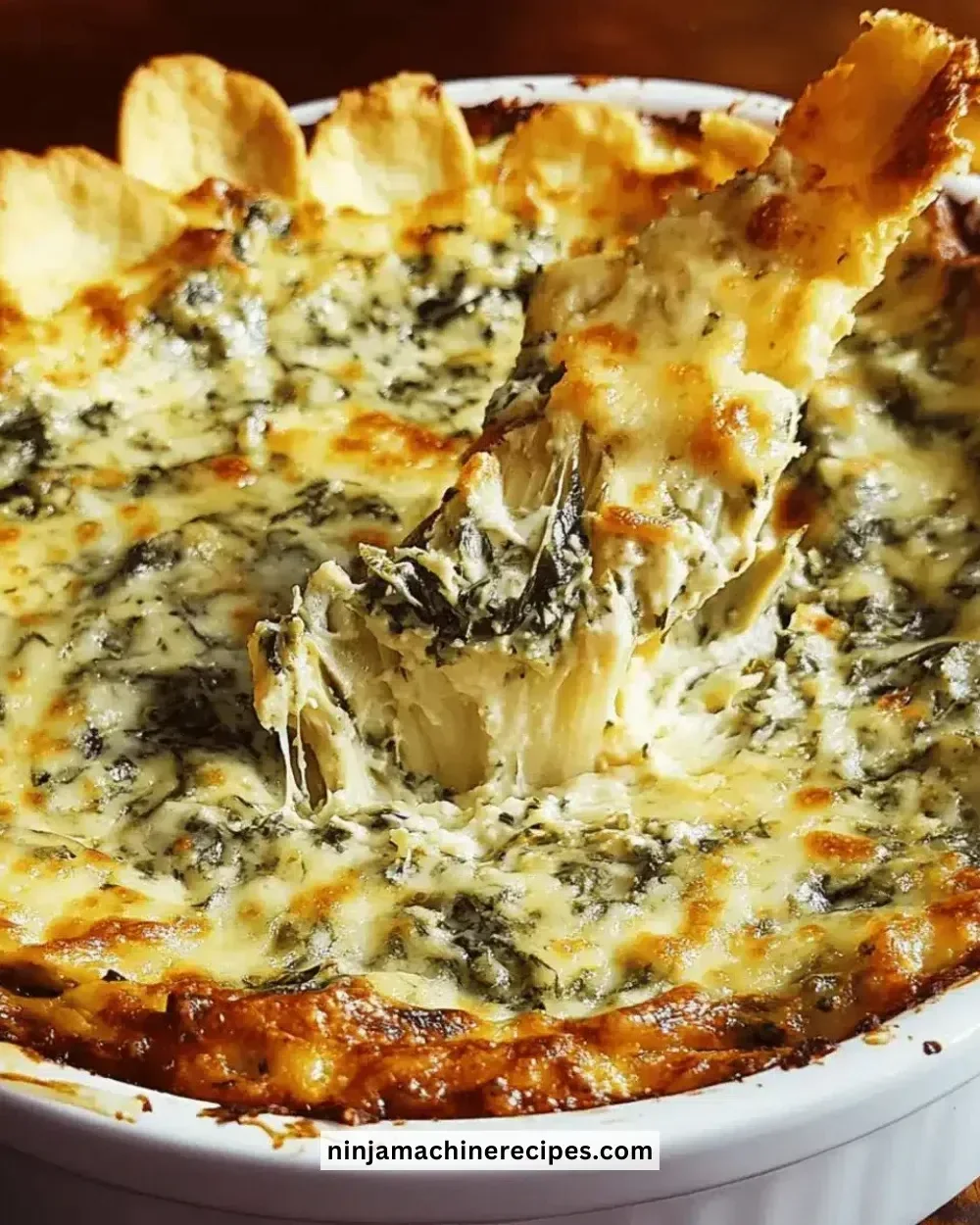 Creamy spinach artichoke dip served in a dish with cheese on top