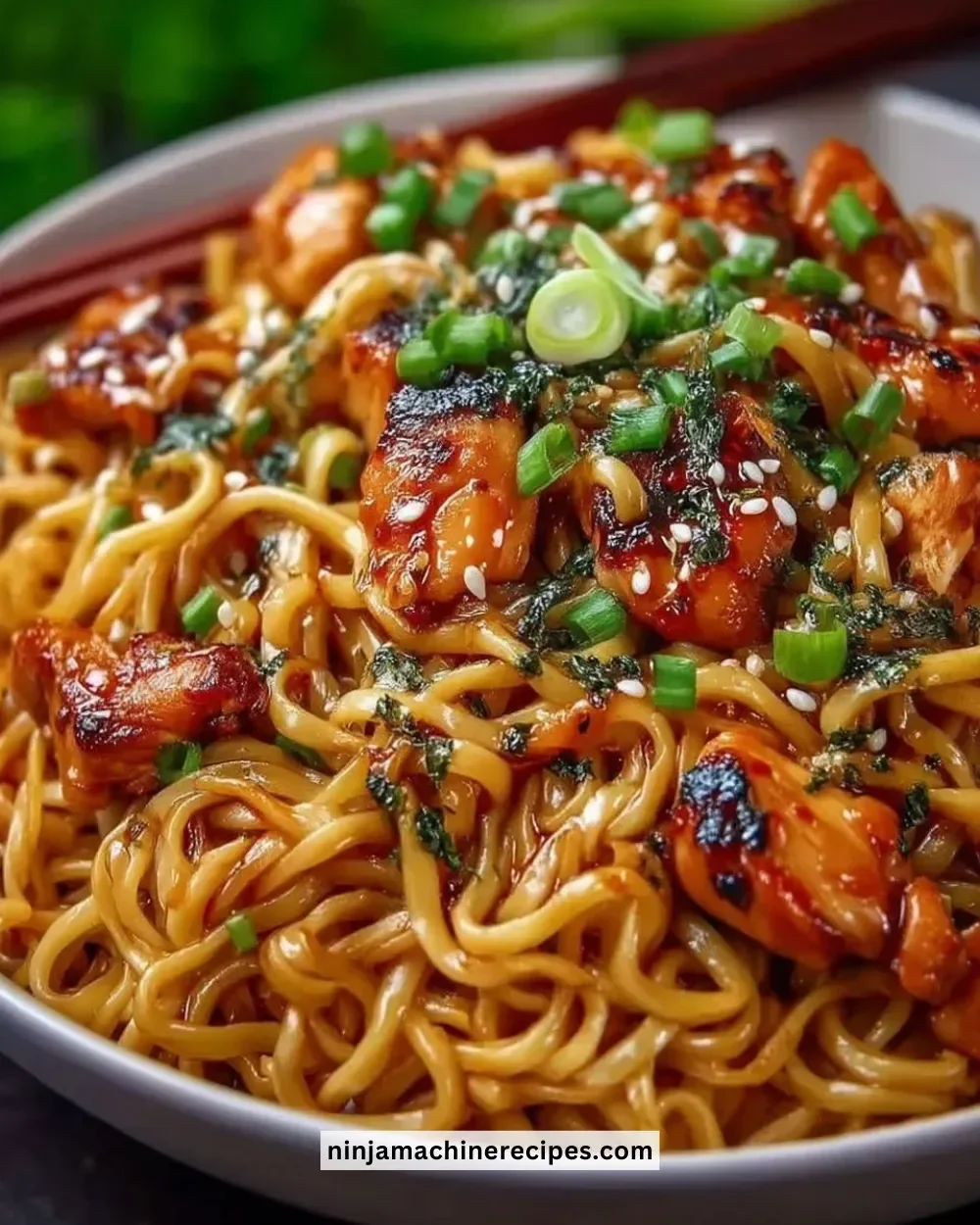 Plate of easy garlic chicken noodles garnished with herbs and vegetables.