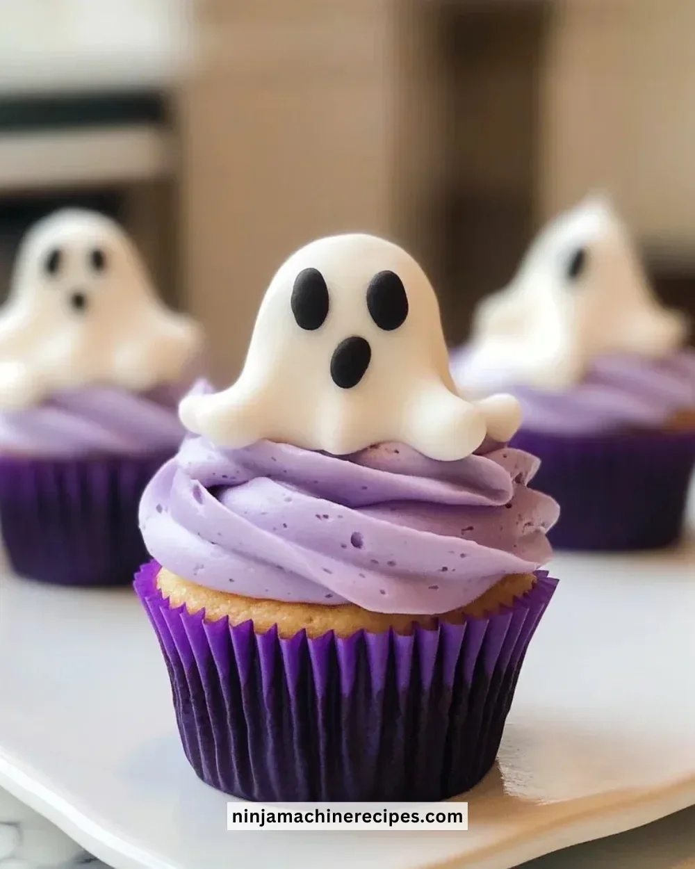 Halloween ghost cupcakes decorated with frosting and candy eyes.