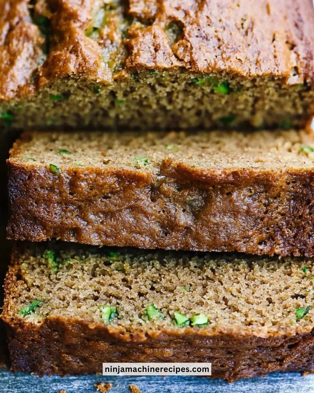 Slice of healthy zucchini bread topped with nuts on a wooden table