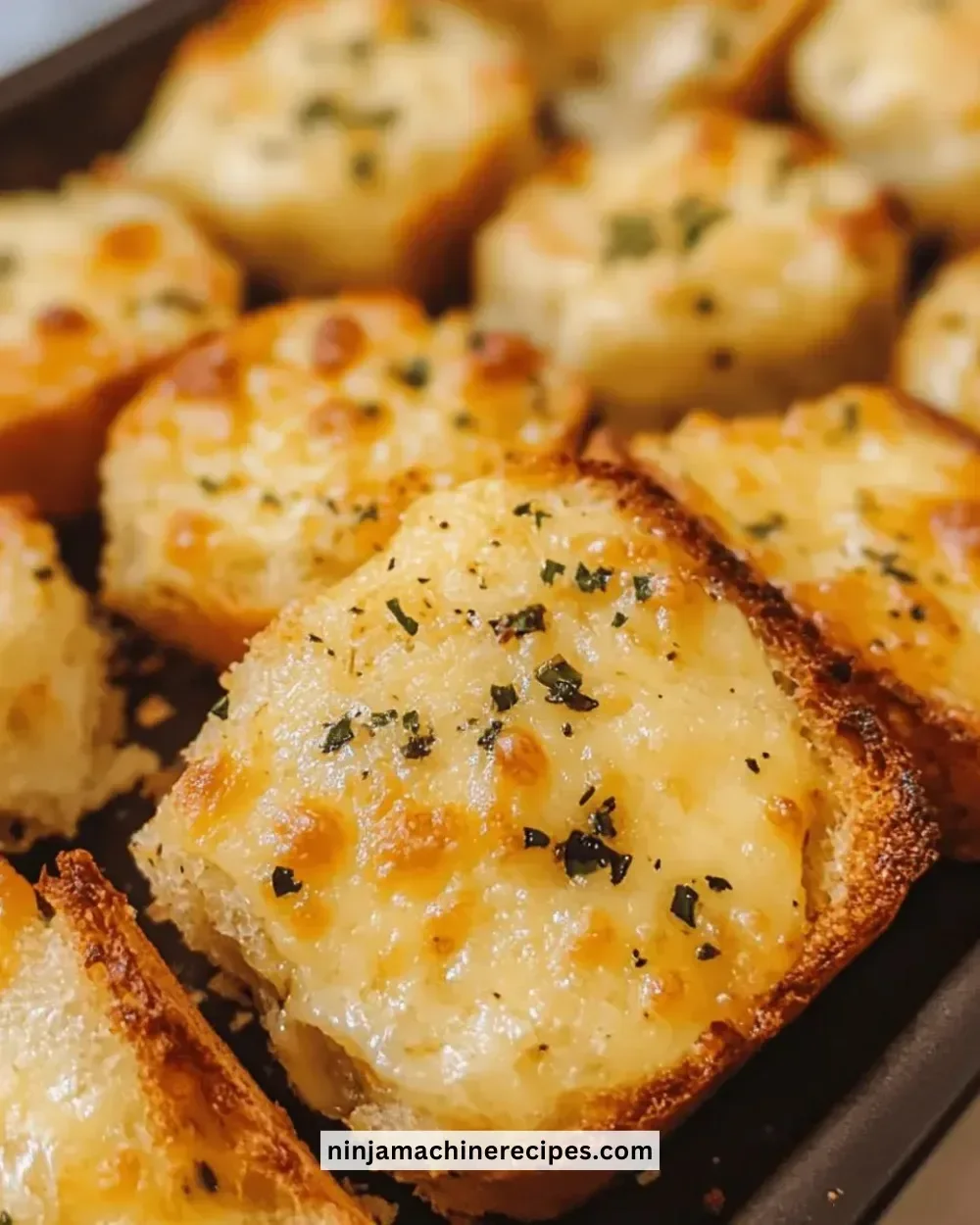 Crispy cheesy garlic bread bites served on a plate, garnished with herbs.
