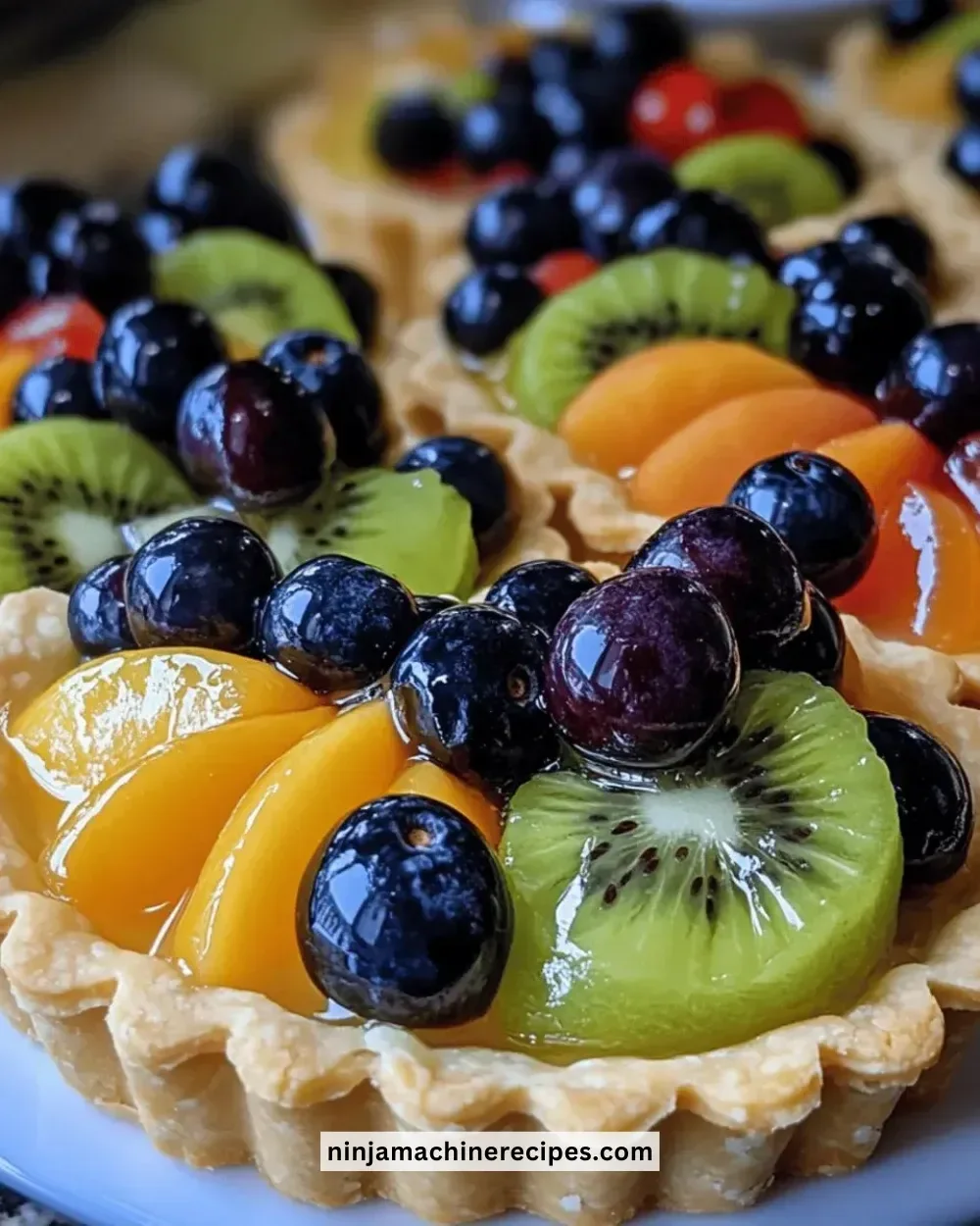 A plate of colorful mini fruit tartlets topped with fresh berries and cream.