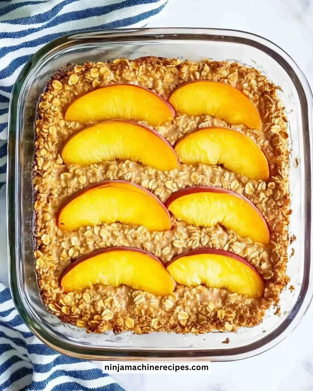 A bowl of peach baked oatmeal topped with fresh peaches and nuts.