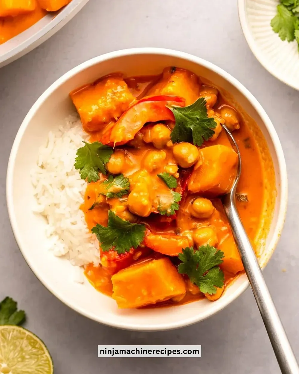 Bowl of pumpkin curry with chickpeas garnished with herbs