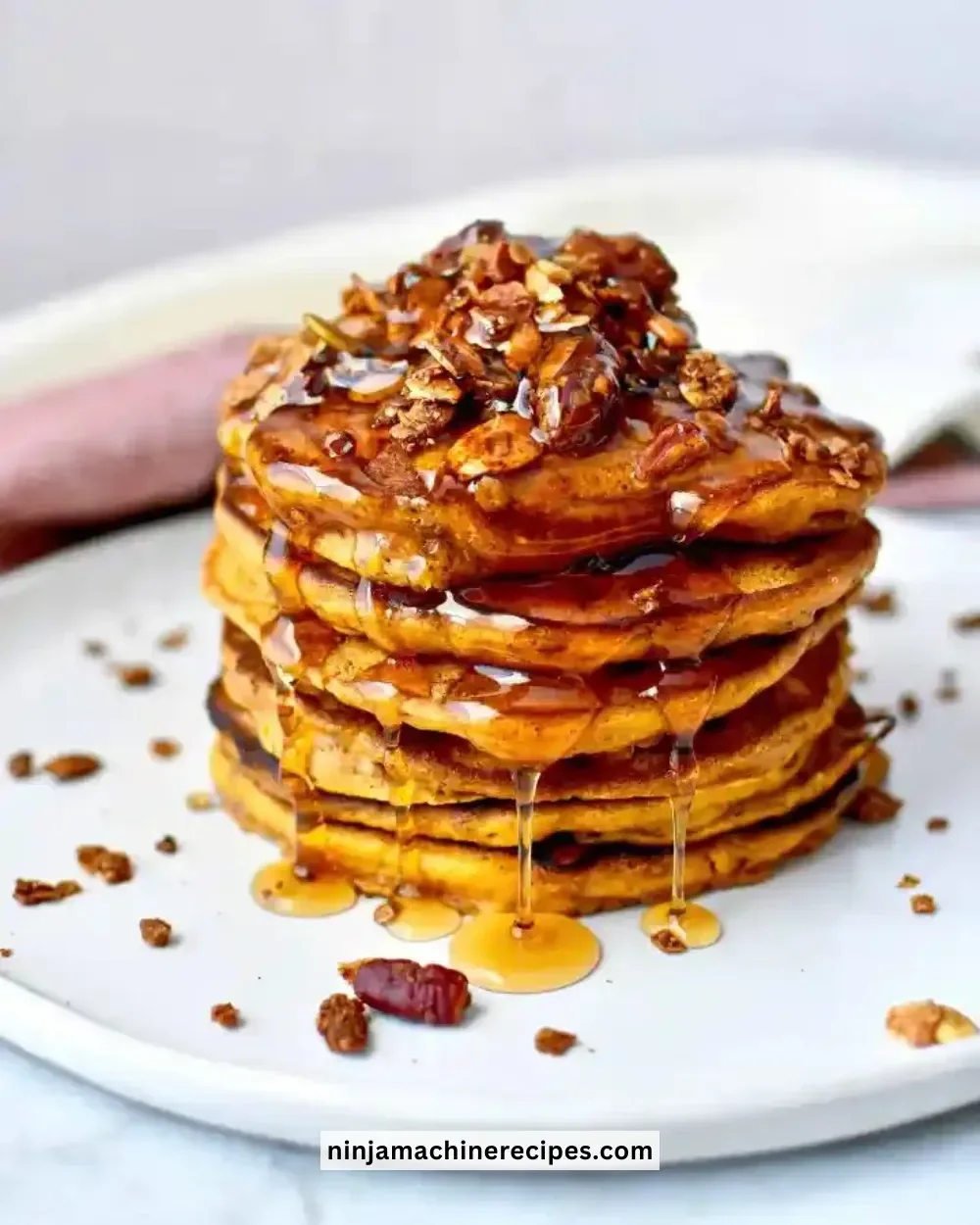 Fluffy pumpkin spice pancakes topped with syrup and whipped cream