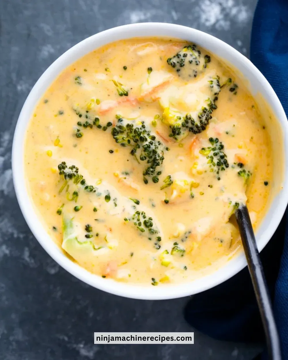 Bowl of creamy broccoli cheddar soup topped with cheese and fresh broccoli