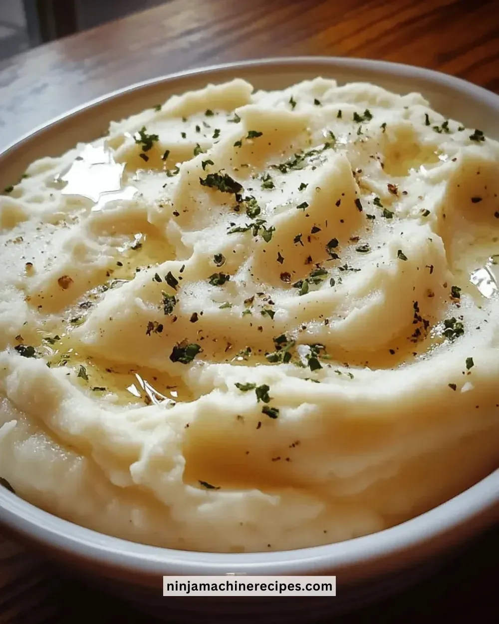 A bowl of creamy garlic mashed potatoes garnished with fresh herbs.