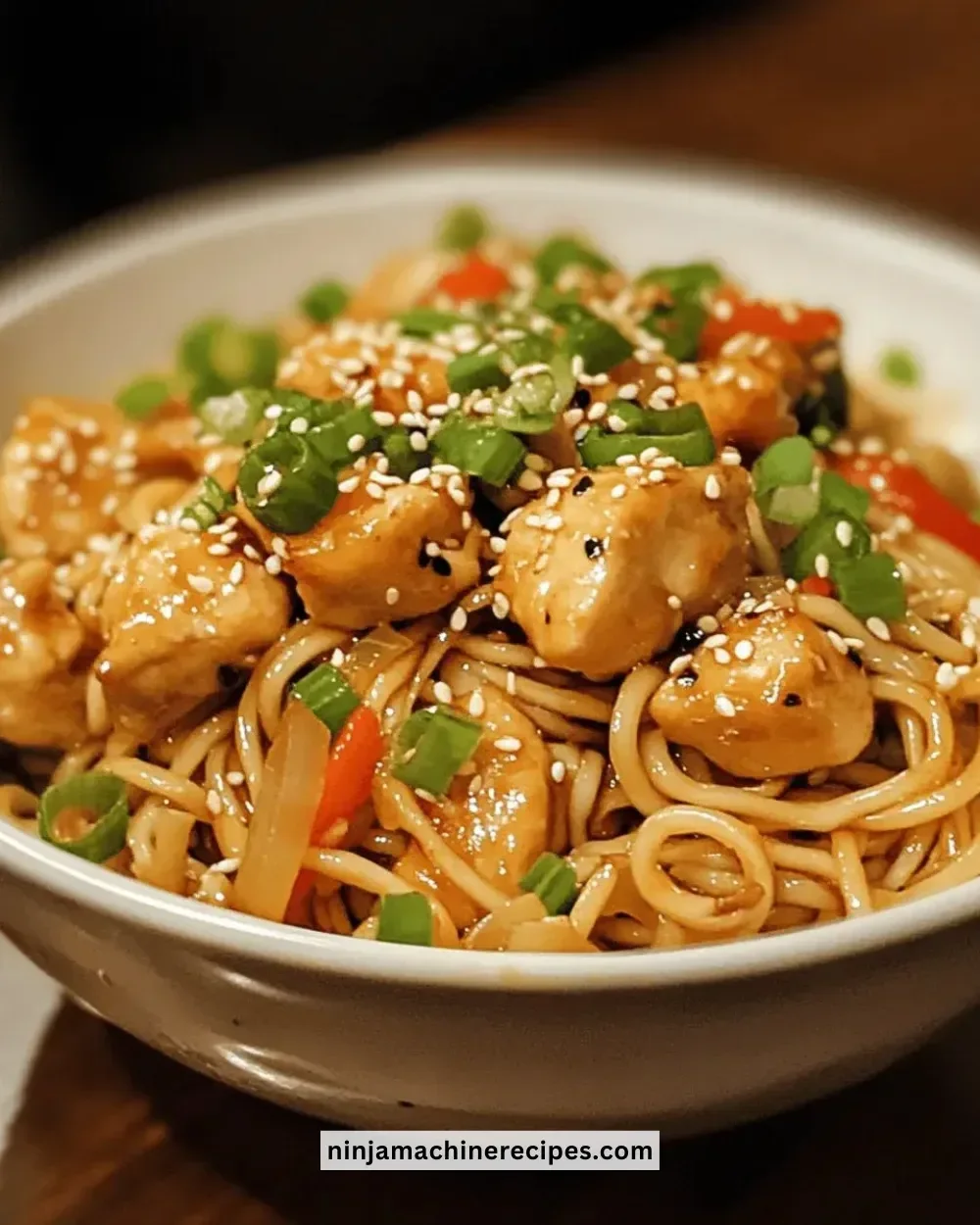 Bowl of Easy Asian Sesame Chicken Noodles garnished with vegetables.