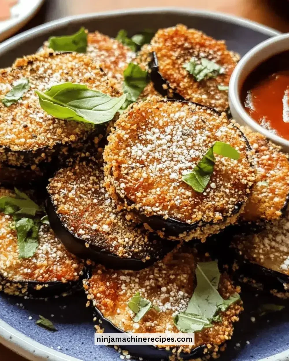 Plate of easy crispy eggplant vegetarian bites garnished with herbs.