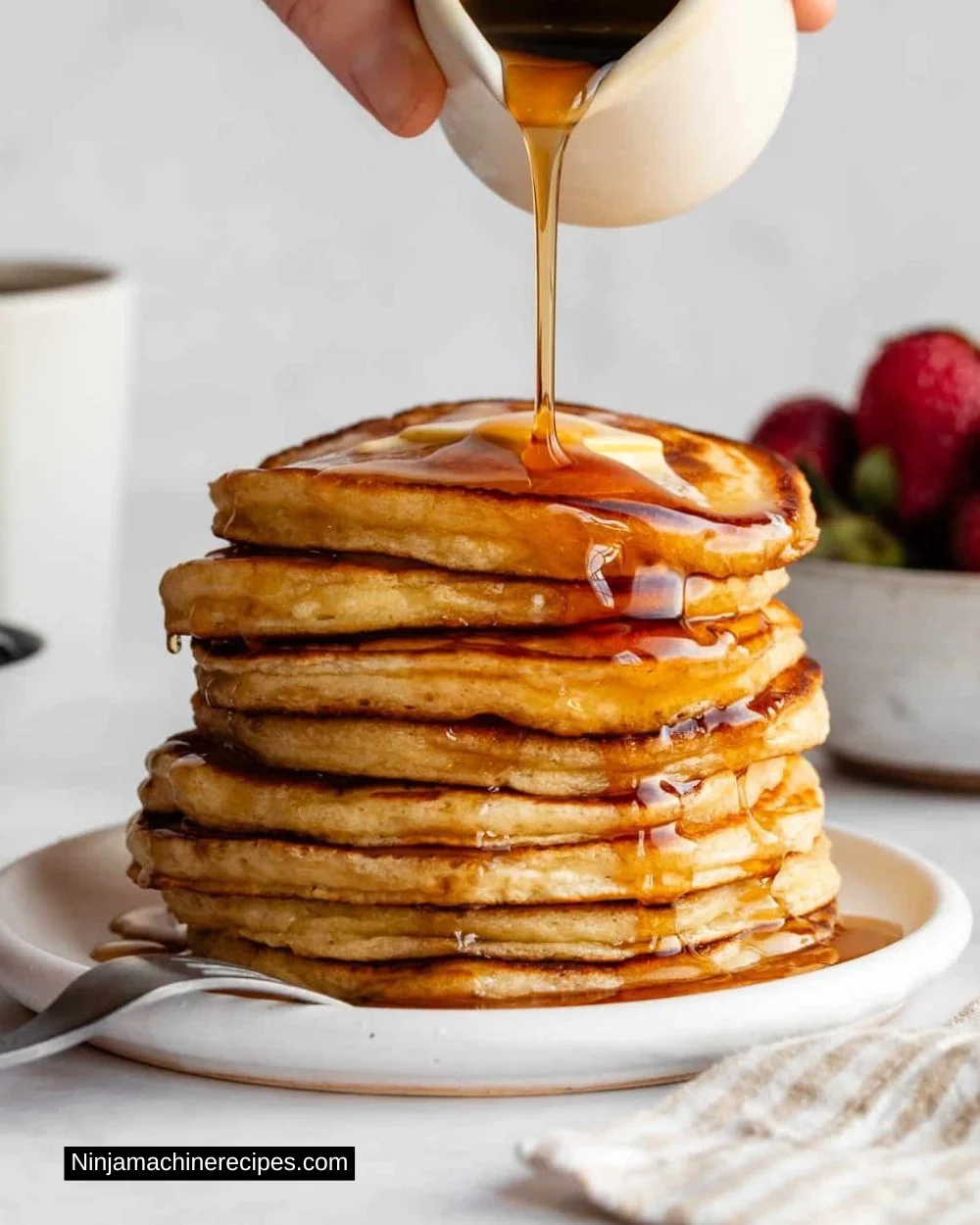Stack of fluffy buttermilk pancakes topped with syrup and berries