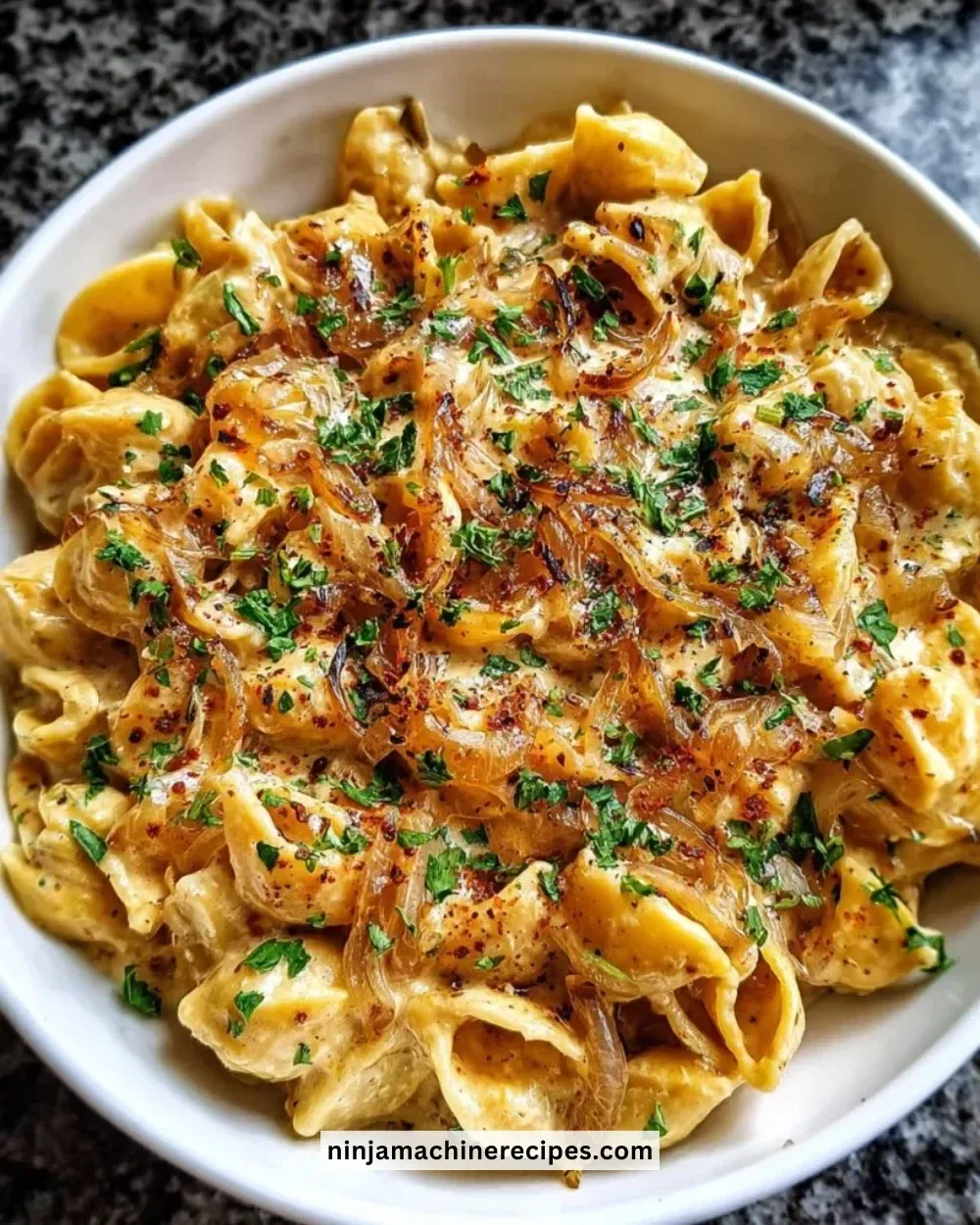 Creamy French Onion Pasta in a bowl garnished with herbs and cheese