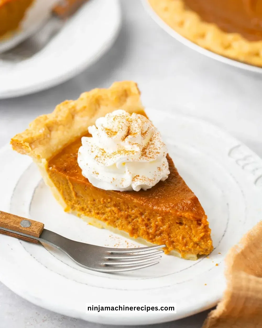 Slice of healthy pumpkin pie topped with whipped cream on a plate