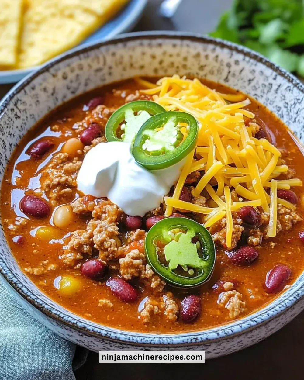 Bowl of healthy turkey chili topped with herbs and served with bread on the side