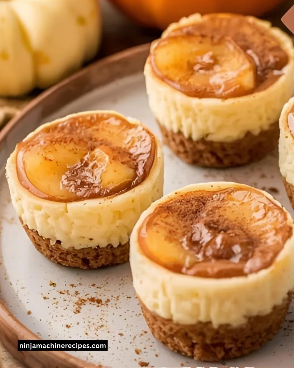 Mini apple pie cheesecake bites served on a plate, garnished with cinnamon and caramel.