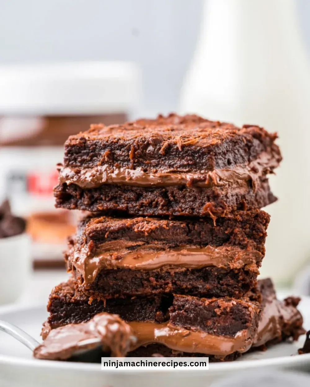 Nutella stuffed brownies topped with chocolate drizzle on a plate