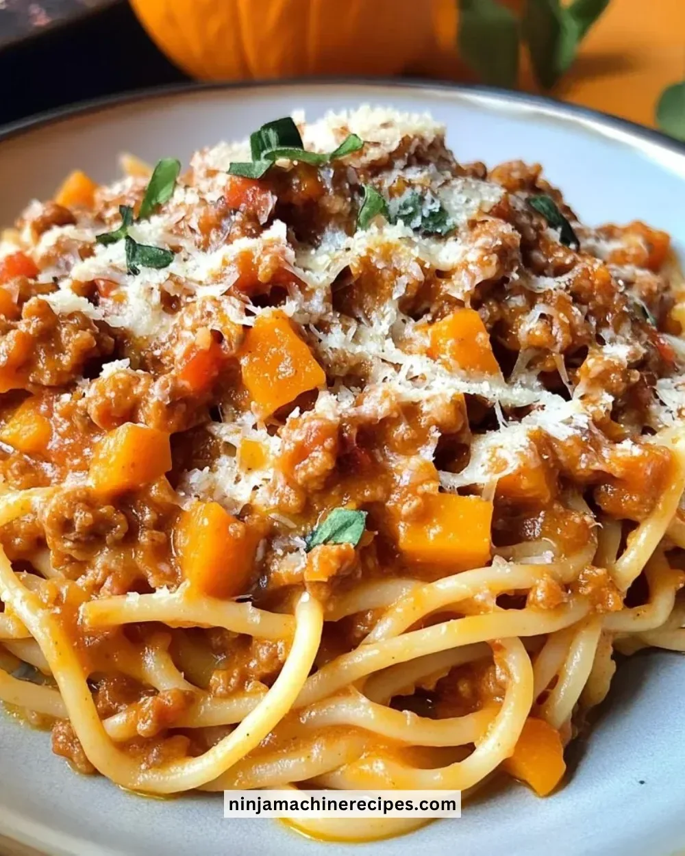 A bowl of savory Pumpkin Bolognese topped with fresh herbs and cheese