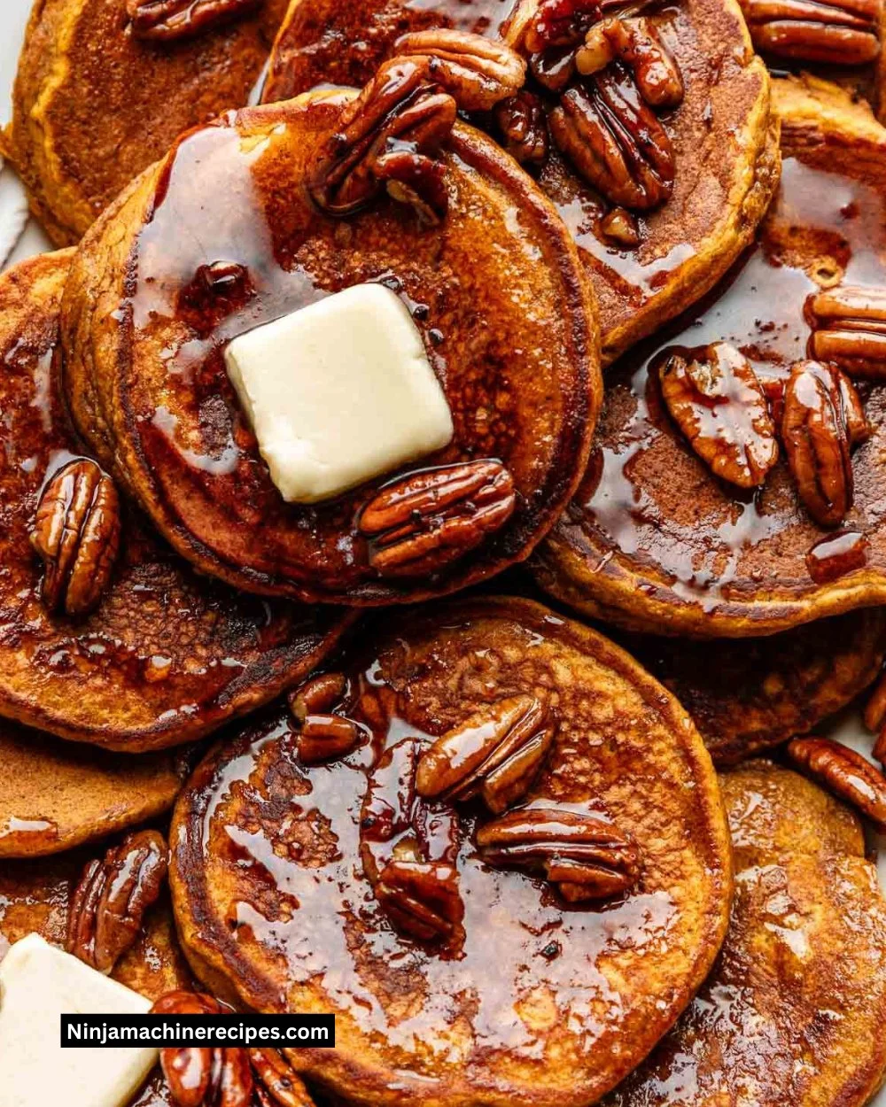 Stack of delicious pumpkin pancakes topped with syrup and whipped cream