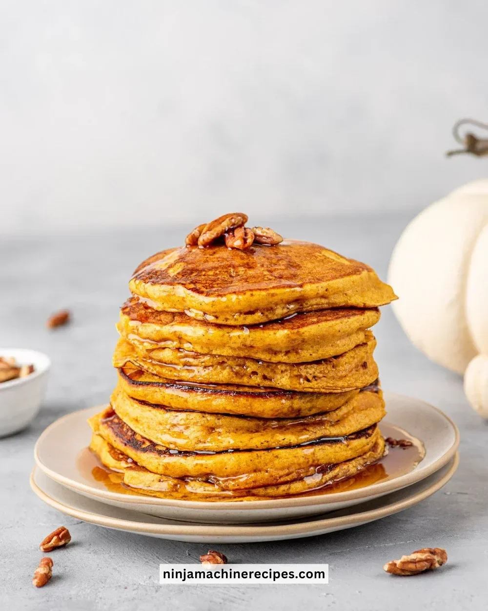 Stack of delicious pumpkin spice pancakes drizzled with syrup and topped with whipped cream.