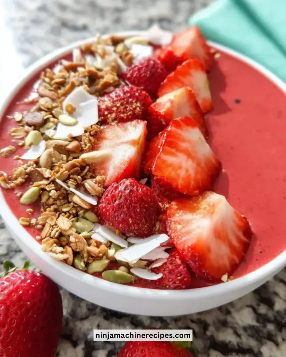 Colorful strawberry smoothie bowl topped with fruits and seeds.