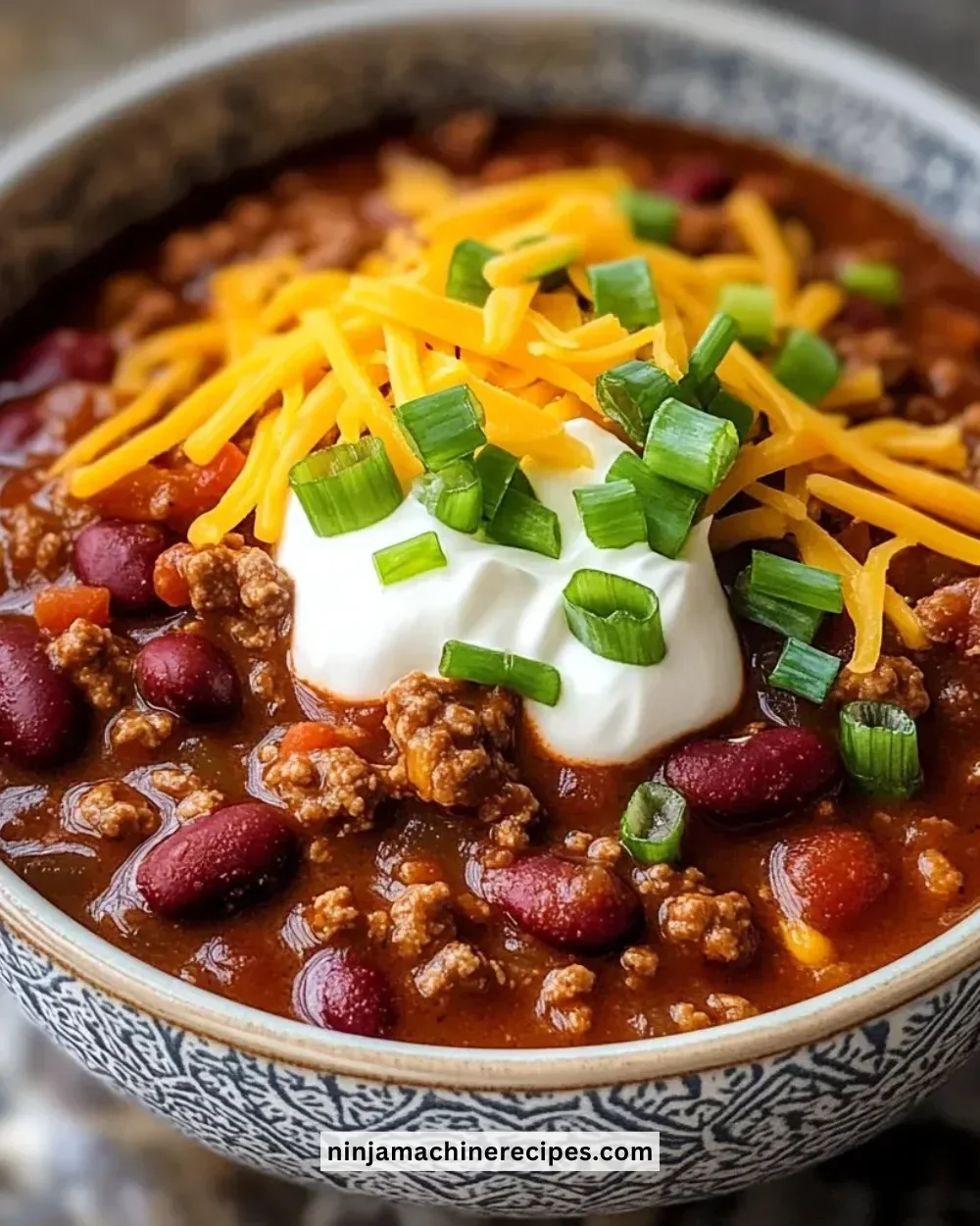 Delicious bowl of the best chili recipe topped with cheese and herbs.