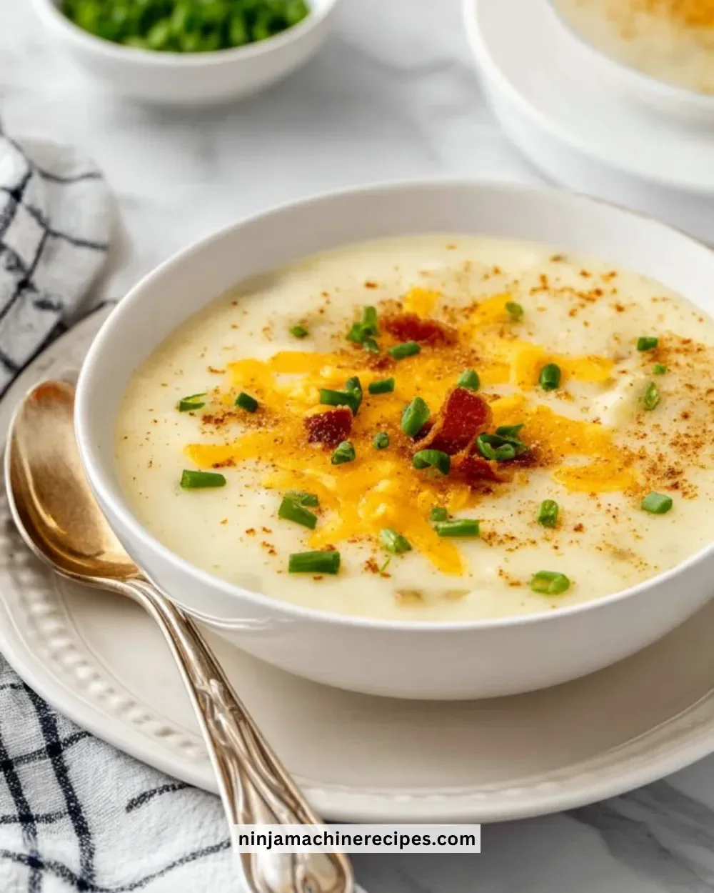 Bowl of creamy baked potato soup topped with cheese and green onions