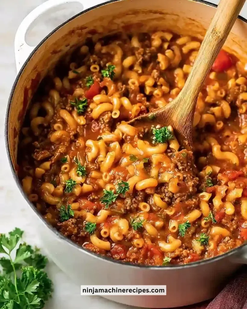 Delicious classic ground beef goulash served in a bowl with pasta and green herbs
