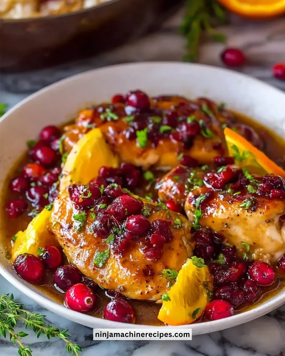 Cranberry Orange Chicken served on a plate garnished with fresh herbs.