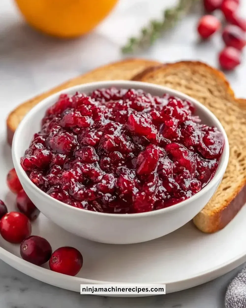 Jar of vibrant cranberry orange jam spread on toast