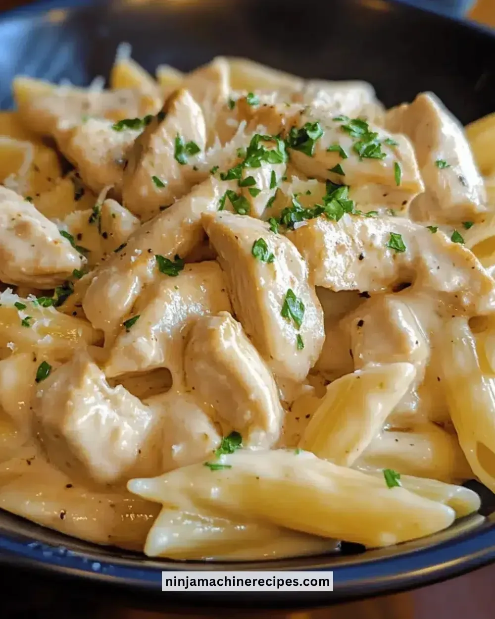 Creamy garlic chicken pasta served in a bowl with herbs and parmesan cheese garnish.