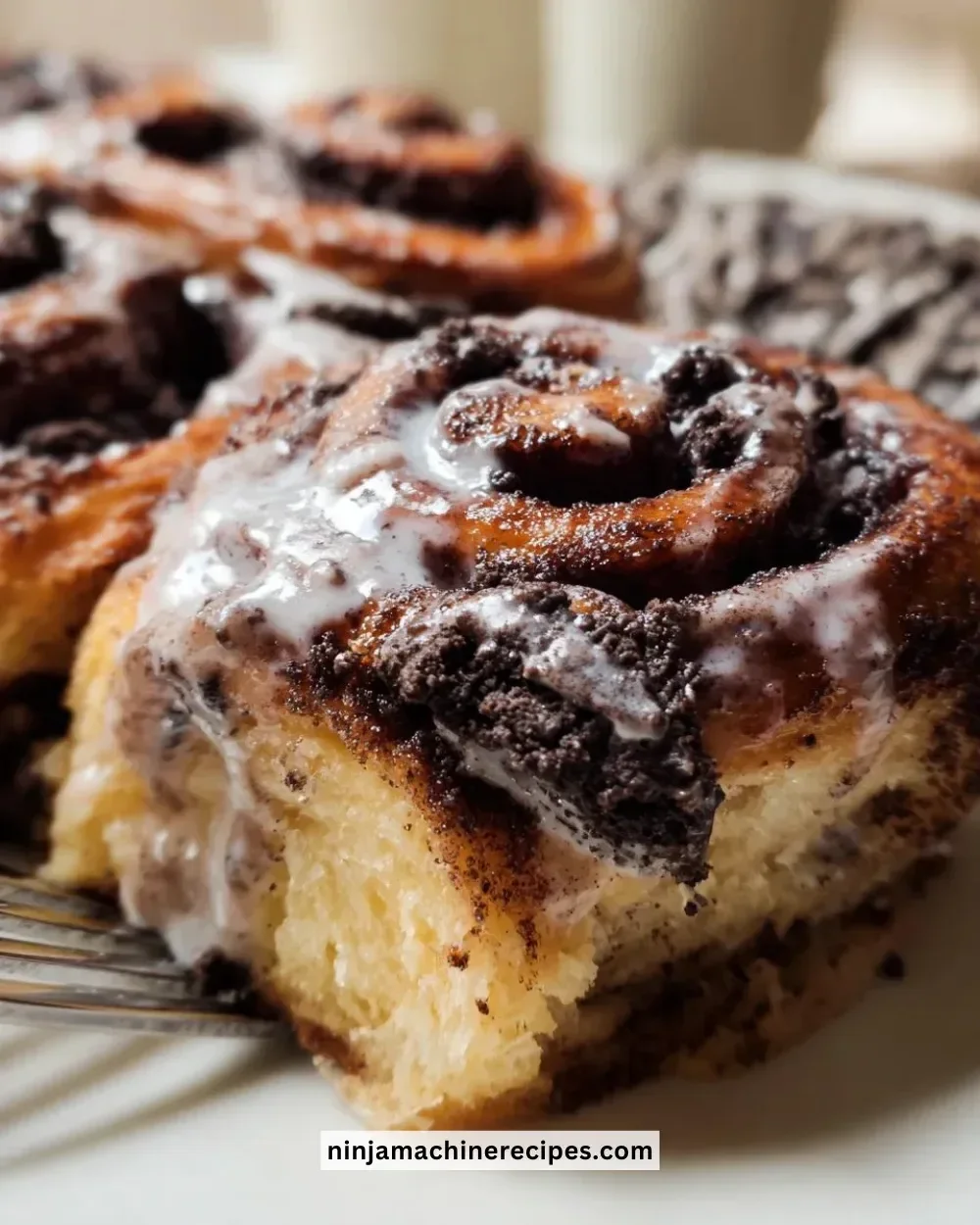 Freshly baked Oreo cinnamon rolls drizzled with icing on a plate