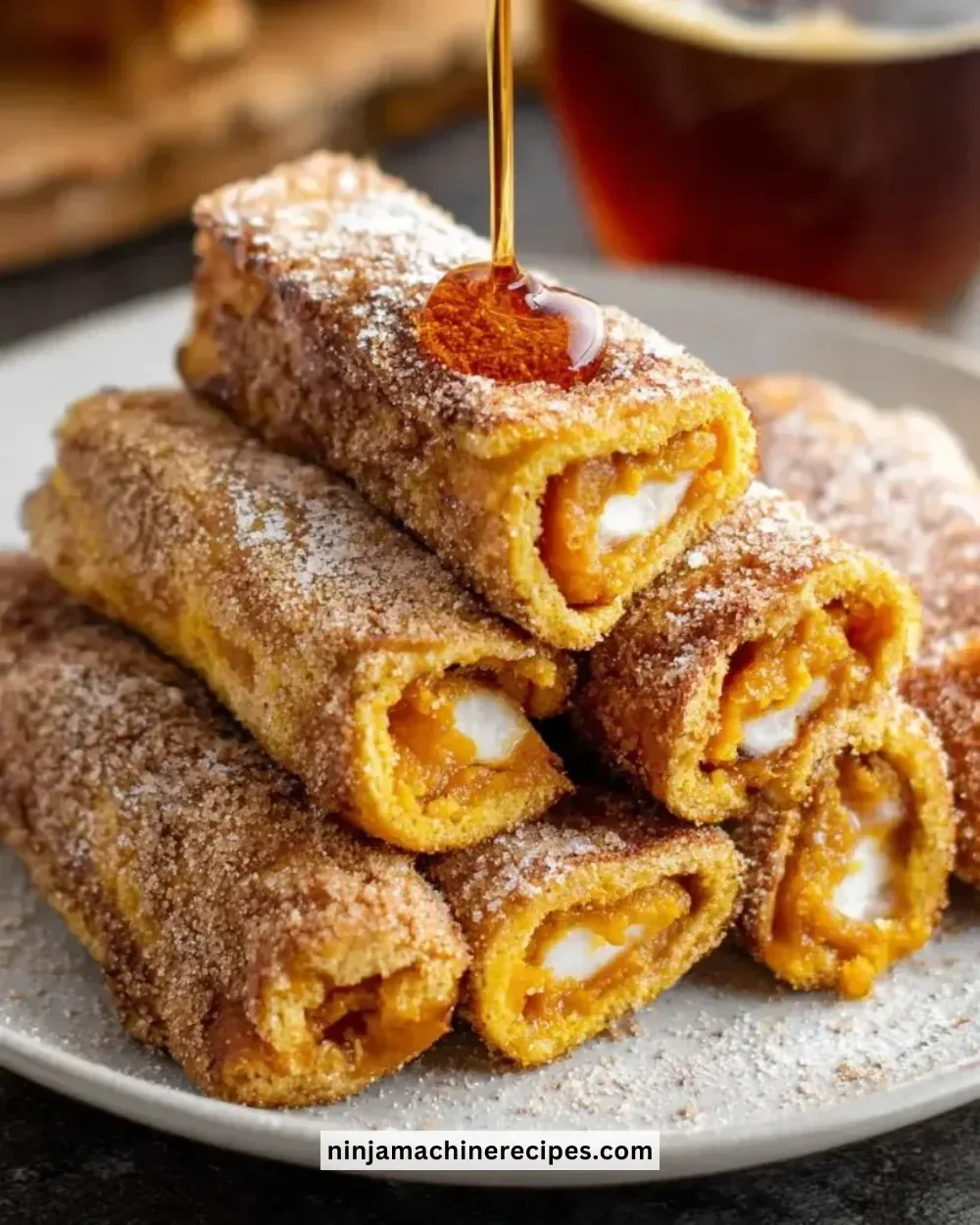 Pumpkin French Toast Roll-Ups with a dusting of powdered sugar and maple syrup