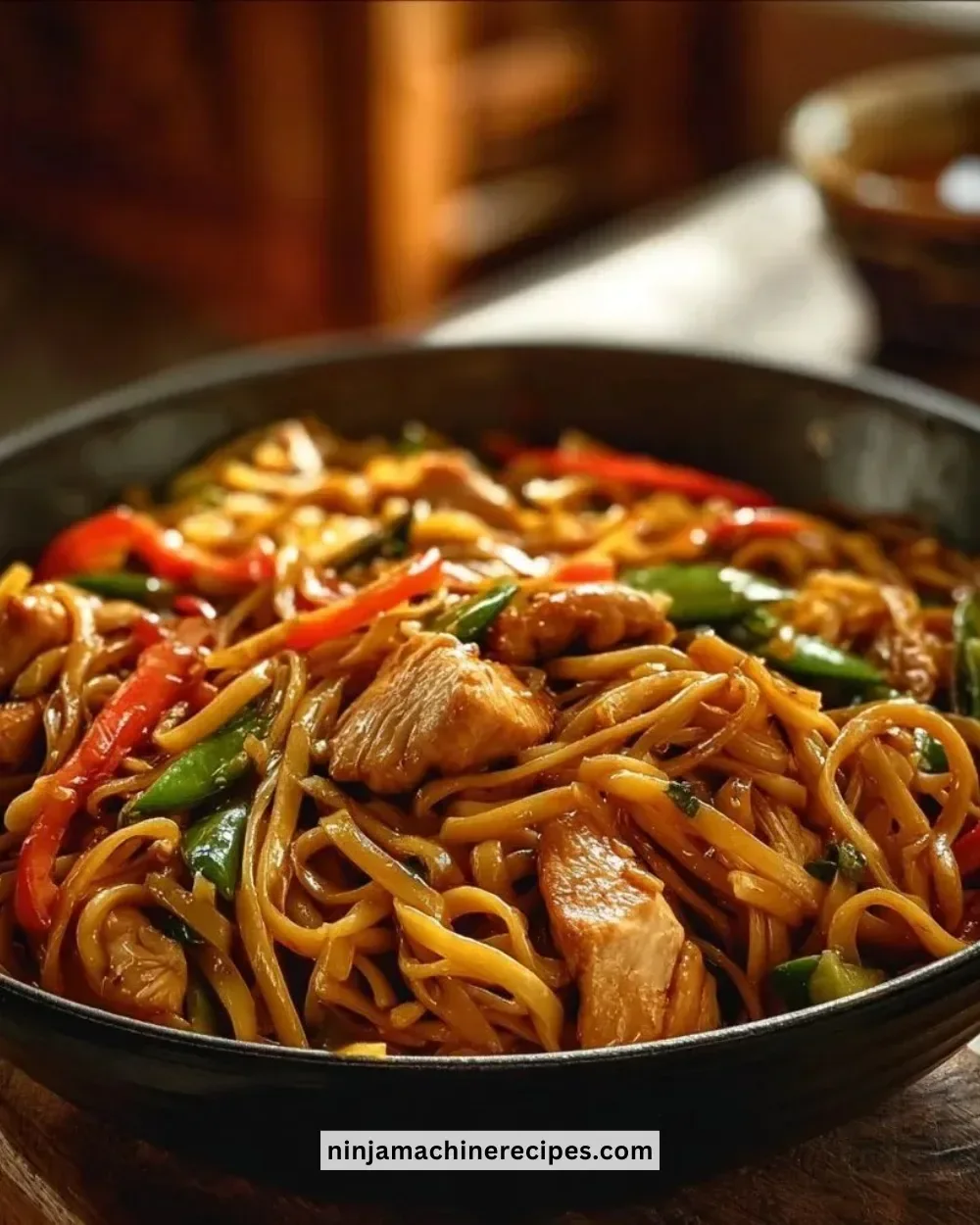 Quick and easy chicken lo mein served in a bowl with colorful veggies.