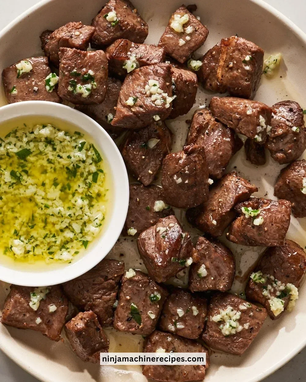 Delicious air fryer steak bites served on a plate with herbs.