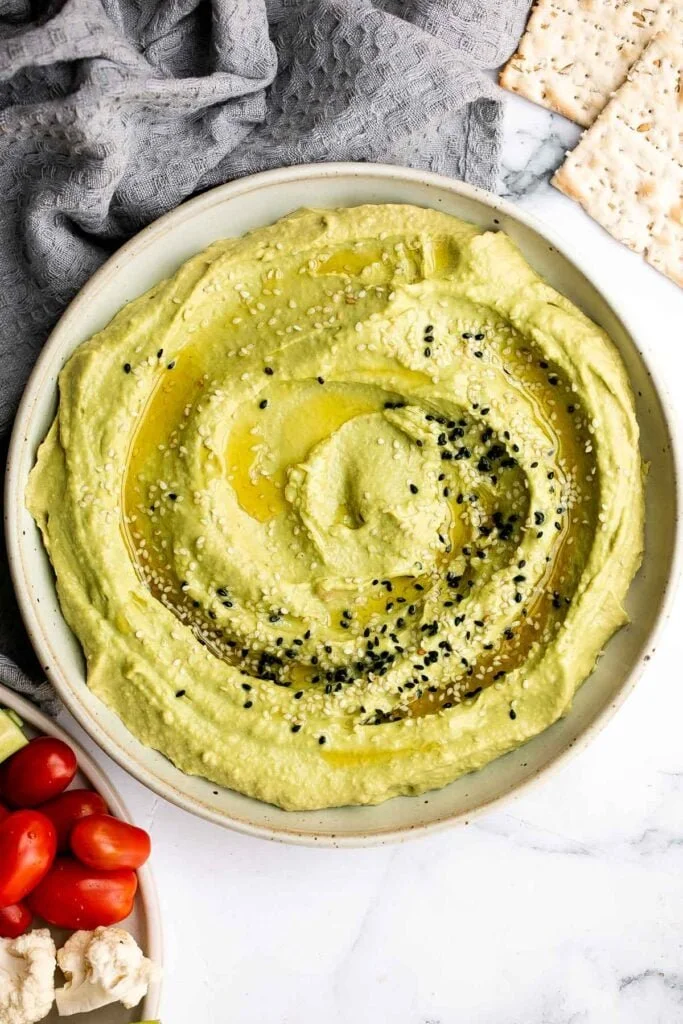 Bowl of fresh avocado hummus with olive oil and pita bread