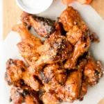 Baked BBQ chicken wings served on a platter with dipping sauce