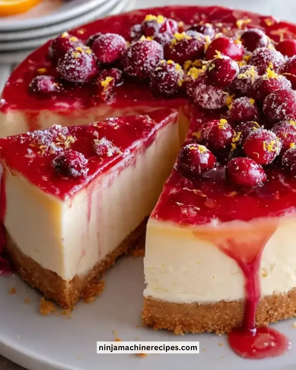 Slice of Cranberry Orange Cheesecake topped with fresh cranberries and orange zest
