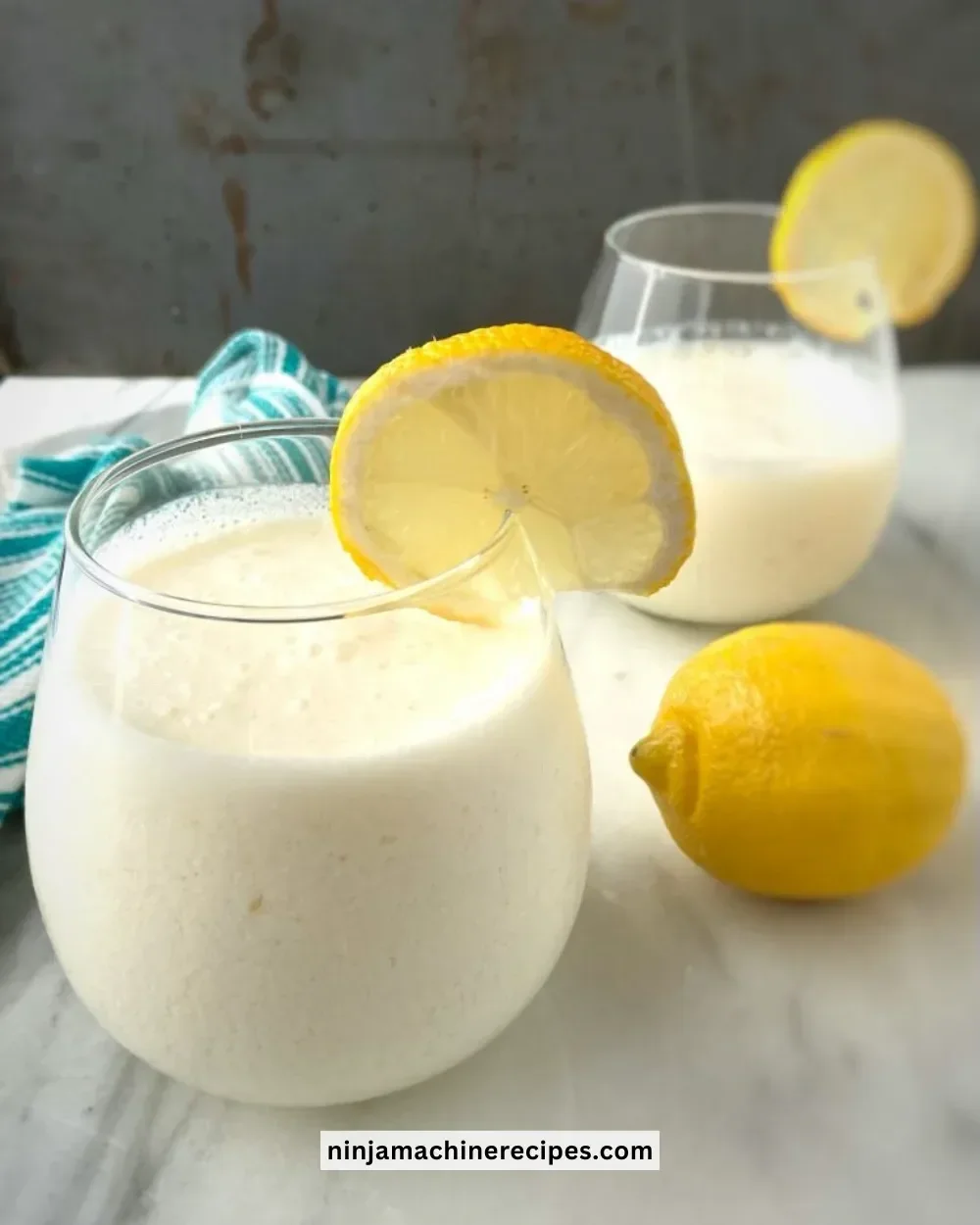 Creamy lemonade slushies served in a glass with lemon slices