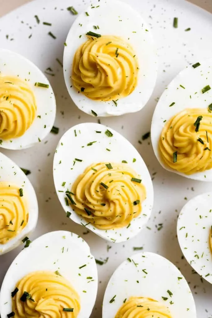 Delicious deviled eggs garnished with paprika and herbs on a serving platter.