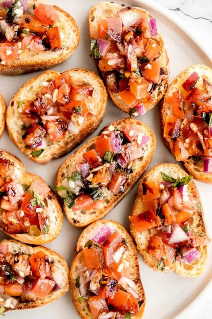 Easy tomato bruschetta with balsamic glaze served on toasted bread.