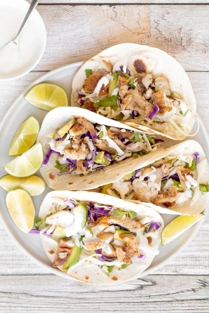Delicious fish tacos topped with lime crema, served on a plate.