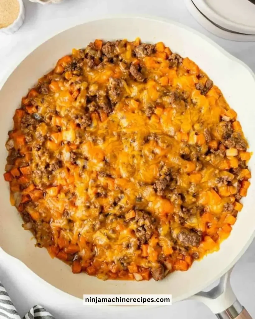 Ground beef and sweet potatoes dish served in a bowl garnished with herbs.