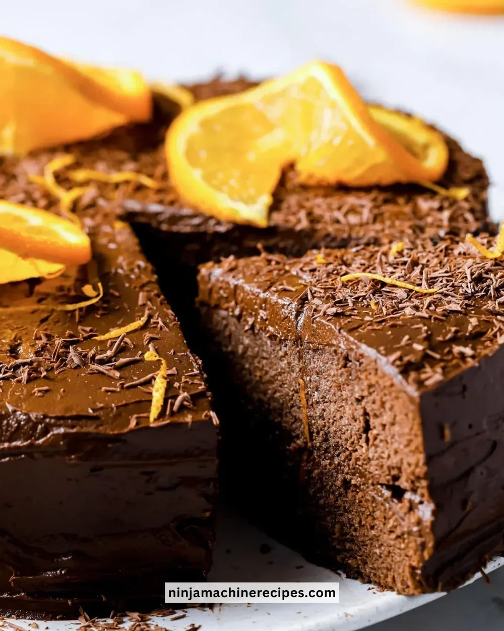 Sliced Healthy Chocolate Orange Cake topped with orange slices and chocolate drizzle.