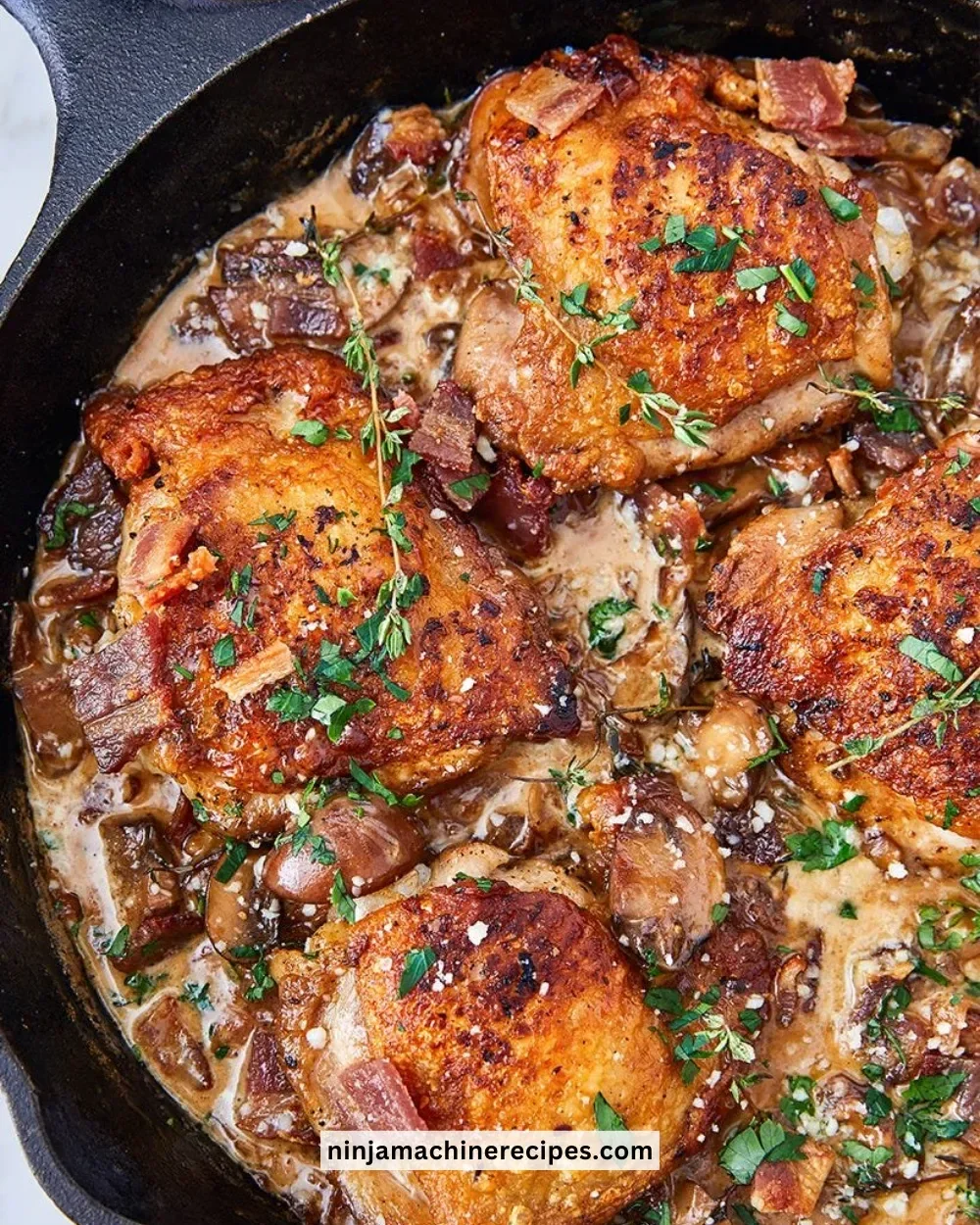 Keto Bacon Chicken Thighs topped with creamy garlic sauce on a plate