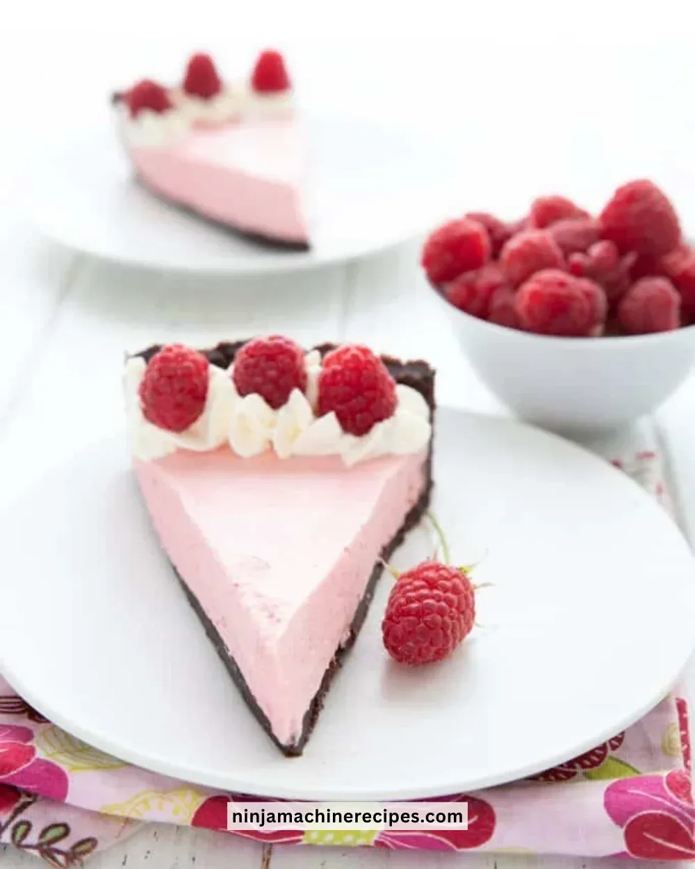 Delicious Keto Raspberry Mousse Tart topped with fresh raspberries and whipped cream