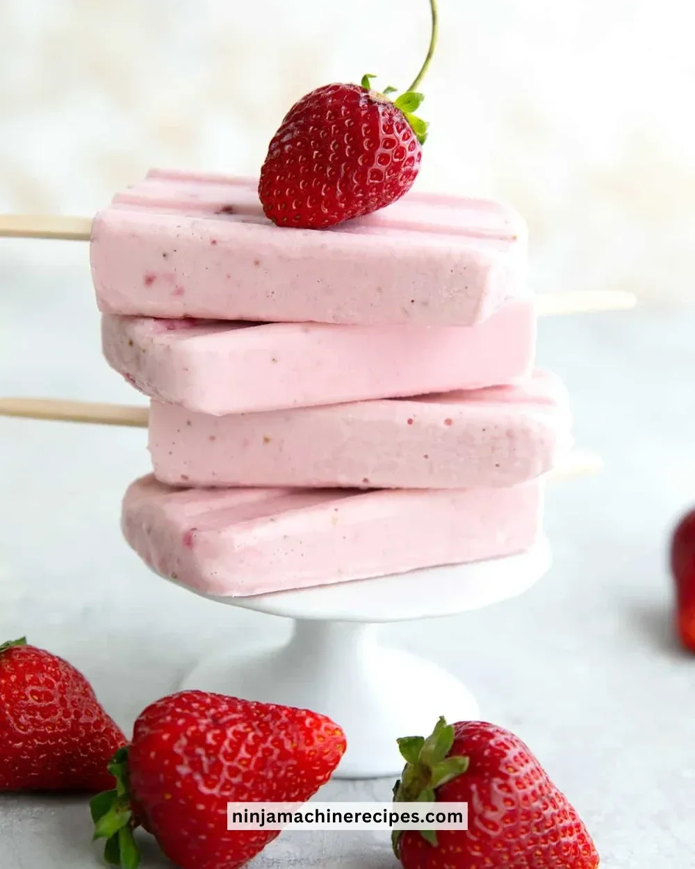 Keto strawberry cheesecake popsicles on a wooden board, ready to enjoy.