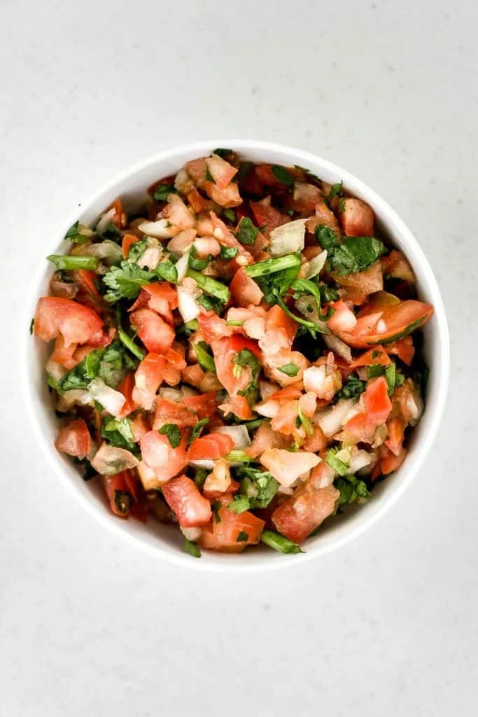 A bowl of colorful Pico de Gallo Chunky Salsa with tomatoes, onions, and cilantro.