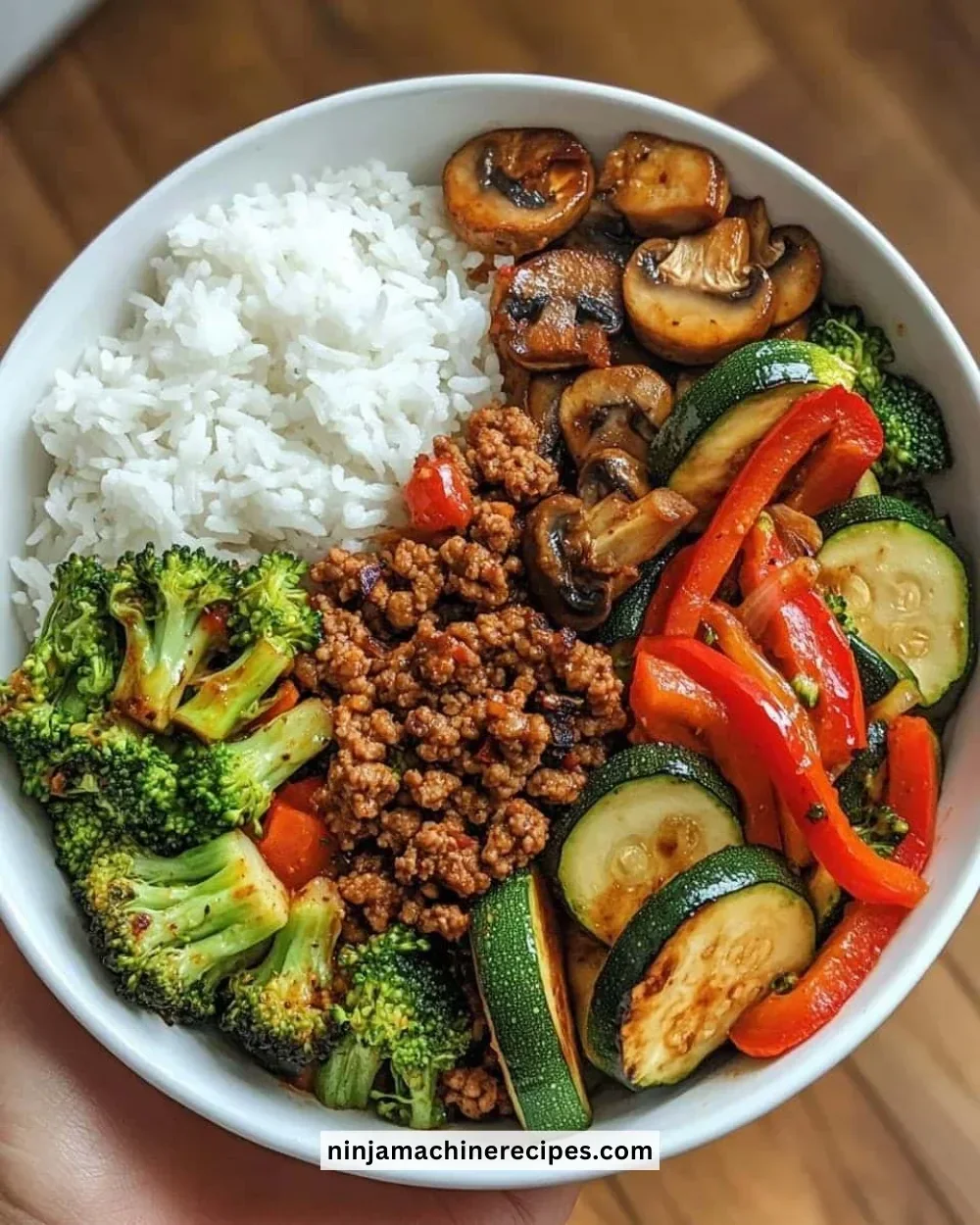 Spicy ground beef stir-fry bowl with garlic vegetables and rice on a plate.